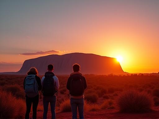 Travelers watching the sunrise over Uluru
